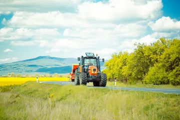 Tuinposter Farm tractor drives on road © Volodymyr