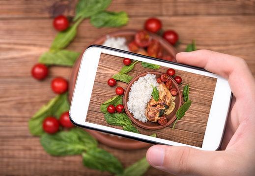 Hands taking photo spinach and cheese stuffed chicken breast  with rice. with smartphone.
