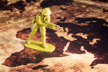 yellow toy soldier in battle action on vintage map, war concept.