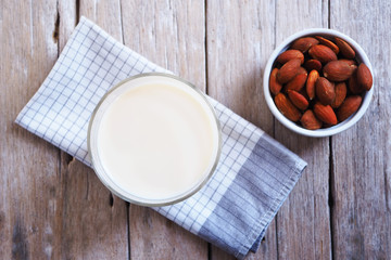 Top view of a healthy glass of almond milk on an old wooden table.