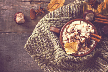 Hot cocoa with marshmallows with spices on the old wooden boards. Coffee, cocoa, cinnamon, nuts, star anise, cozy sweater.Autumn Still Life