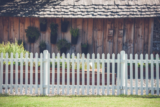 White picket fence in front af a wooden shed