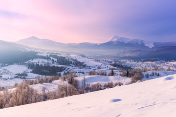 Amazing winter sunset over mountain snowy ridge, countryside landscape in soft pink light