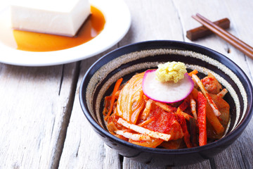 Close up of a tradition Korean kimchi in a bowl on a wooden table.