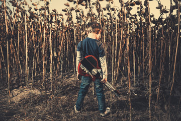 boy with guitar at dry sunflowers field