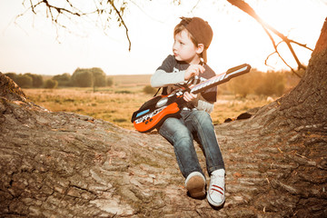 boy with guitar at fall meadow tree sunset