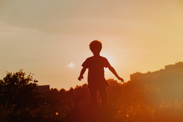silhouette of little boy running at sunset