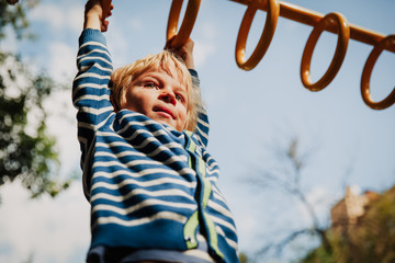 little boy playing on monkey bars at playground
