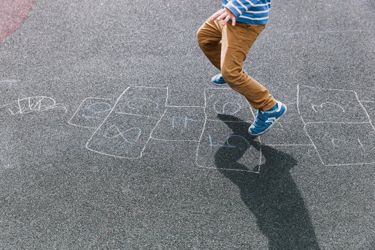 kid playing hopscotch on playground, kids outdoor activities