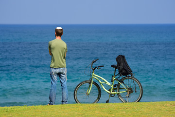 Fototapeta premium Lonely jewish man standing on the sea shore, looking at the horizon and thinking. 