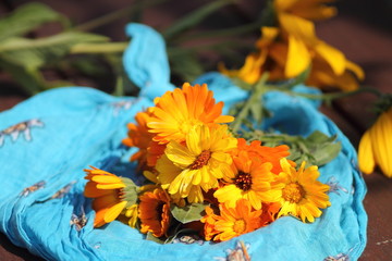 Bouquet of calendula flowers on cyan scarf with edelweiss ornament.