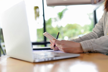 Woman typing text message on smart phone in a cafe. Cropped imag