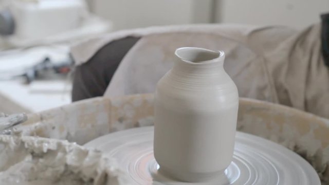 Pottery wheel turning, making vase of white clay ceramic clean hand person