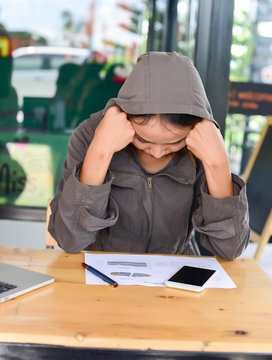 Overworked young woman sitting at the desk and holding his head