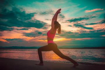 Fototapeta na wymiar Silhouette young woman practicing yoga on the beach at sunset. Vintage tone