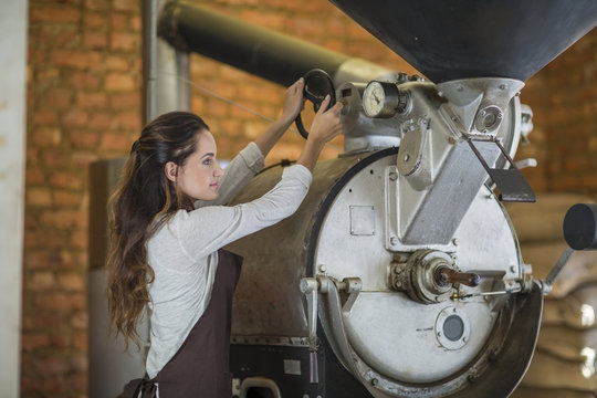 Young Woman Operating Coffee Roasting Machine