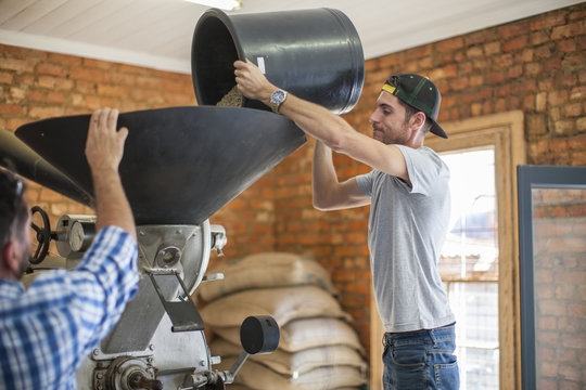 Man pouring coffee beans into a roasting machine