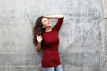 Happy young female model standing against gray wall