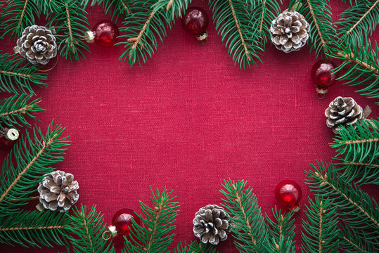 Frame with xmas tree and ornaments on red canvas background. Merry christmas card. Winter holiday theme. Space for text. Happy New Year.