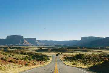 Road trip scene; long road going into scenic canyon landscape in USA