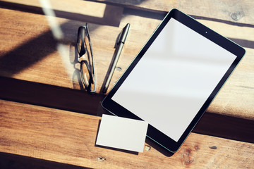 Closeup Modern Tablet Blank White Screen,Glasses Wood Table Inside Interior Coworking Studio.Empty...