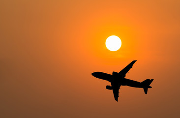Silhouette of big airplane on beautiful orange sunset background, fast aerial transport, traveling and voyage concept