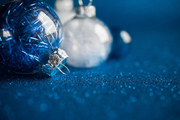 White and blue christmas ornaments on dark blue glitter background with space for text. Merry christmas card. Winter holidays. Xmas theme. Happy New Year. Space for text.