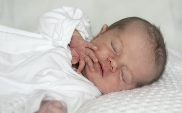 Portrait image of a newborn baby boy, sleeping on a white blanket. 
