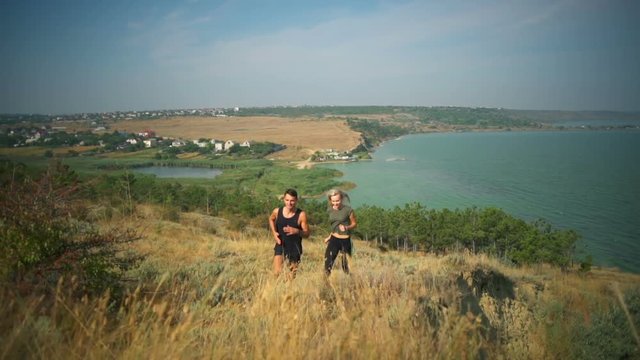 Sportive couple smiling jogging up on hill firth background Slow motion