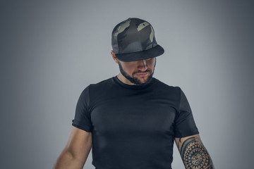 Bearded male in a baseball cap looking down.