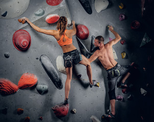 Male and female climbing on an indoor climbing wall.
