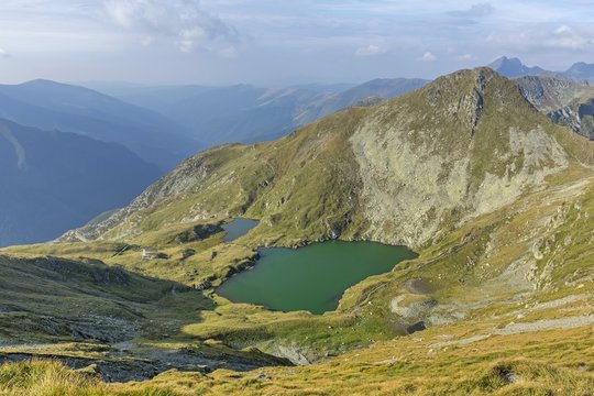 Mountain lake with crystal clear water of emerald color.  Landscape from Capra Lake in Romania and Fagaras mountains in the summer.