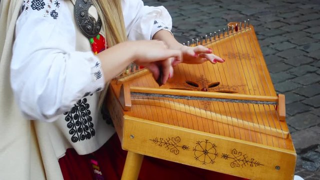The girl in the Latvian national clothes playing the national instrument kokle on the street of Riga.
