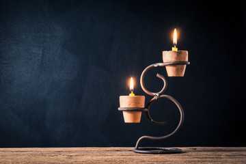 handicraft candlestick with burning candles on old wooden table against art dark background