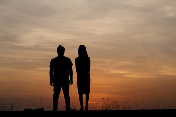 Silhouette man and woman with beautiful the sky at sunset..Backg