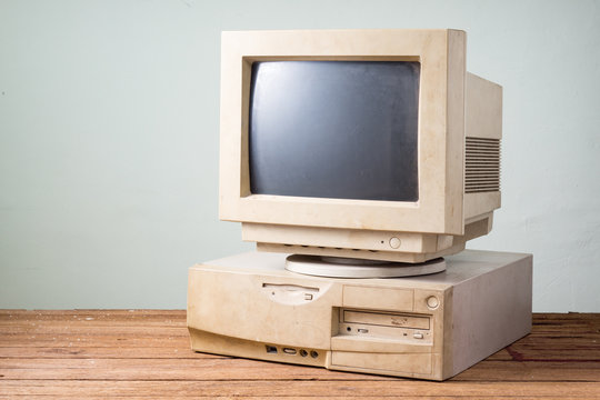 old and obsolete computer on old wood table with concrete wall background