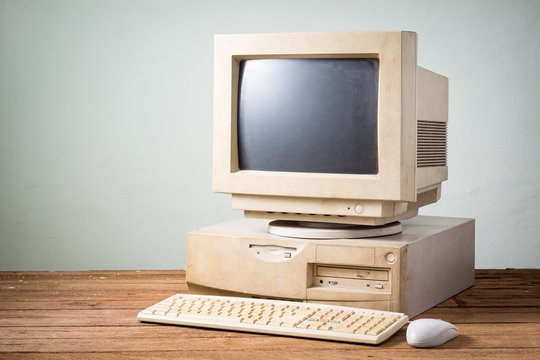 old and obsolete computer on old wood table with concrete wall background