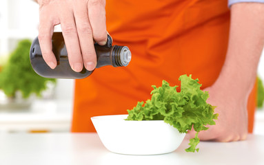 Chef is pouring olive oil over fresh salad in restaurant kitchen. Healthy eating, dieting, slimming and weigh loss concept.