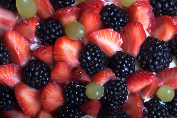 Top of biscuit homemade cake with cream and berries on black bac