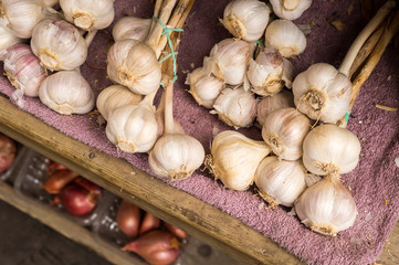 Many heads of garlic drying in a wooden box at the market