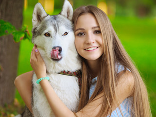 Attractive young woman hugs funny siberian husky dog who shows its tongue