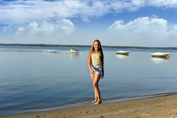 Piękna dziewczynka spaceruje brzegiem jeziora. - obrazy, fototapety, plakaty