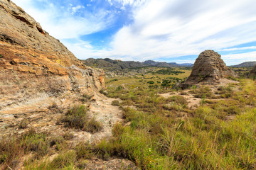Fototapeta na wymiar Steep sharp rocks surrounding a valley with trees and grassland
