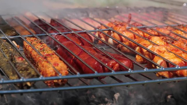 Detalle de varios tipos de carne y embutidos haciendose en la parrilla al aire libre 
