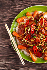 takeawy classic pork on rice with fried in sticky souce carrots, sprinkle of chillie and spring onion.