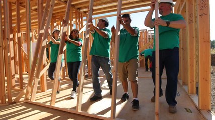 Volunteers working together lifting wall