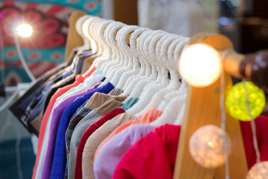 A row of colorful t-shirts, cloth, clothes, pants hanging on hangers