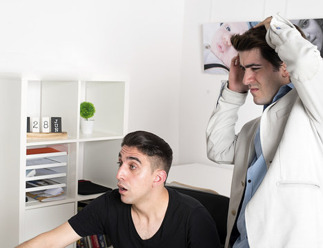 Businessman and his colleague with shocked and terrified faces in office