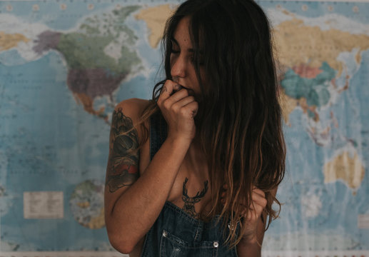 Sexual brunette woman in denim cloth posing on world map background