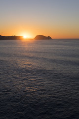 Sea and coast with the sun in the background.